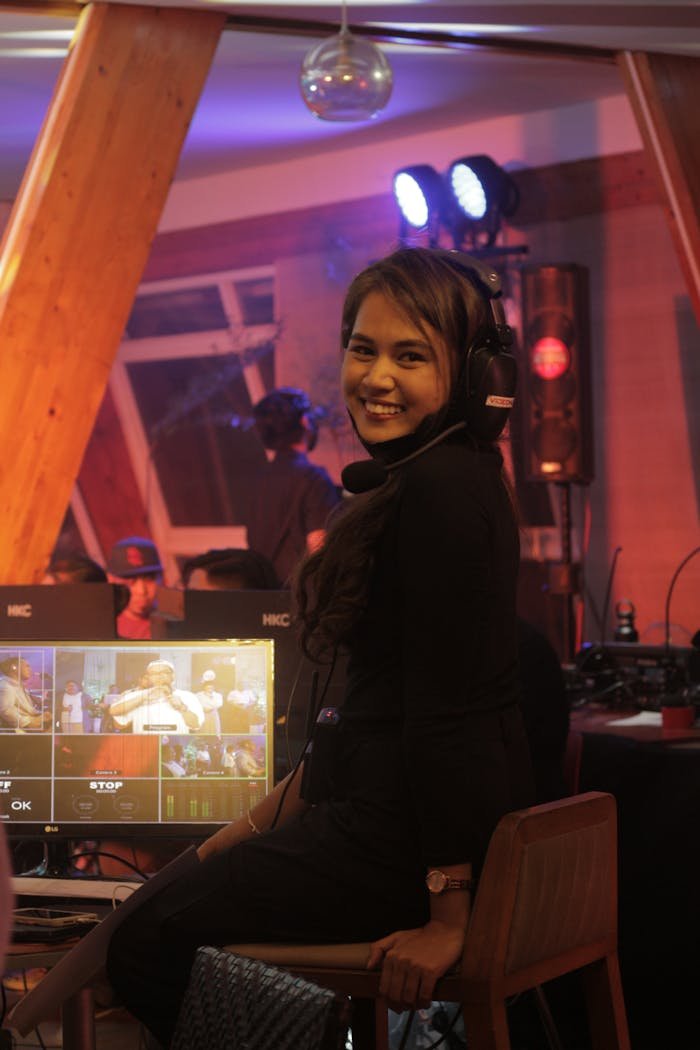 creative Smiling woman wearing headset directing video production on a vibrant film set.