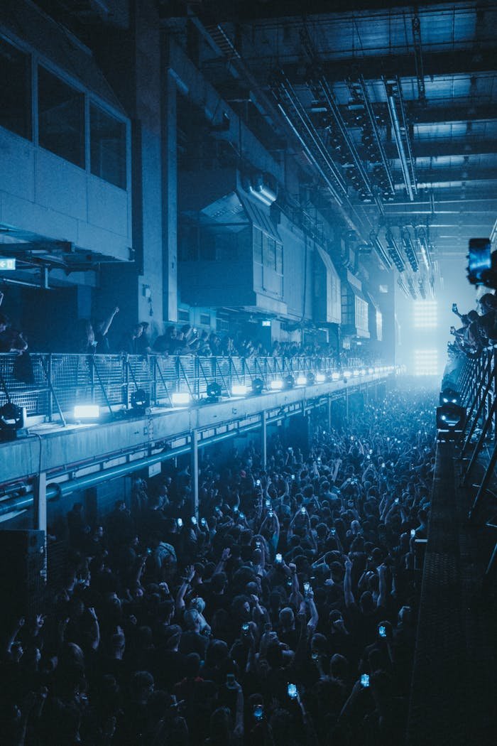 creative-03 Energetic concert crowd inside industrial venue with dramatic lighting and music vibes.