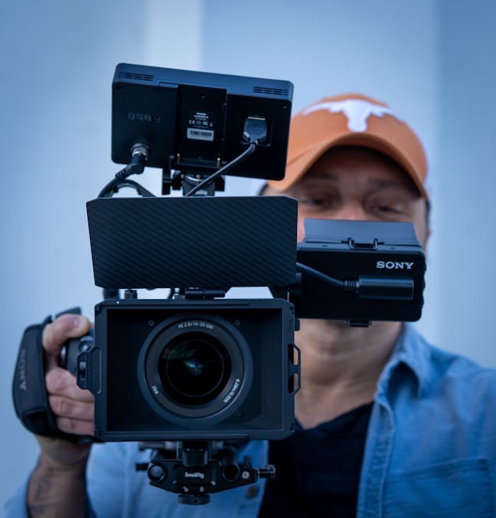 why-choose-us Cinematographer holding a Sony video camera, showcasing advanced filming equipment.